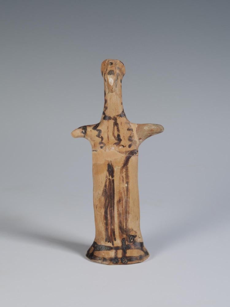 Photograph of terracotta female figurine, frontal, against neutral gray-blue background.