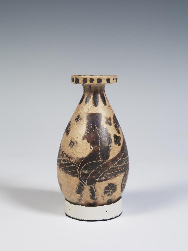 Photograph of an Early Corinthian alabastron, buff clay with brown decoration of a sphinx facing viewer's left, from the side against a neutral gray background.