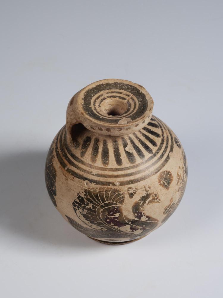 Photograph of small, rounded aryballos, from a high angle, against a neutral gray background.