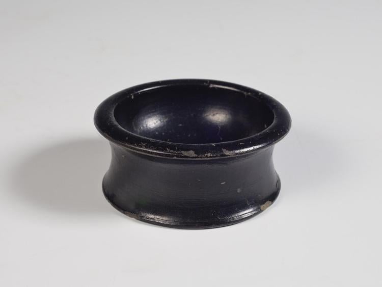 Photograph of all-black salt cellar, from raised but not high angle against a neutral gray background.