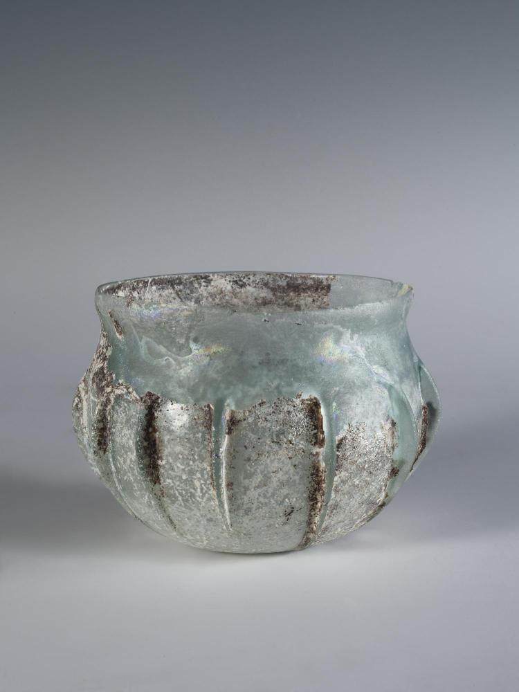 Photograph of a clear glass bowl with a slightly flaring lip, from the side against a neutral gray background.