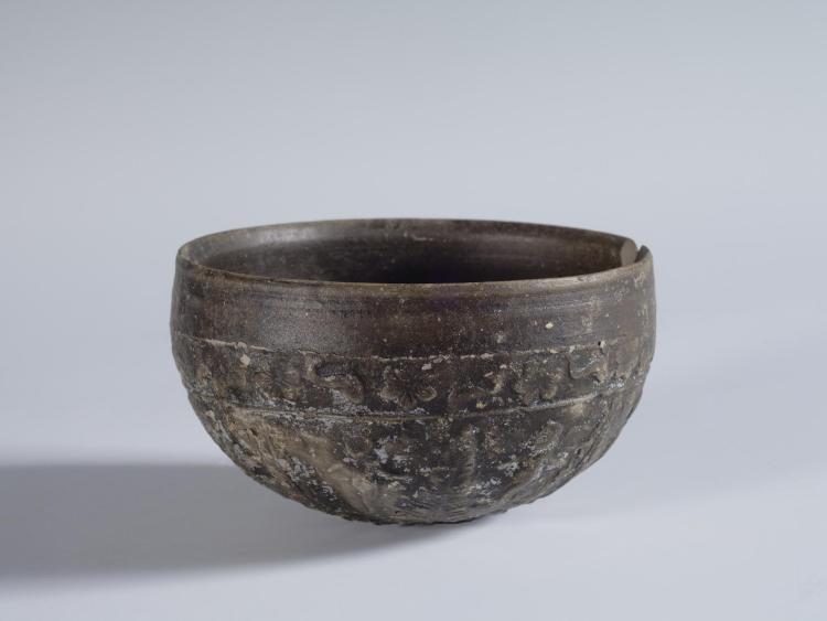 Photograph of a mould-made bowl, from the side against a neutral gray background.