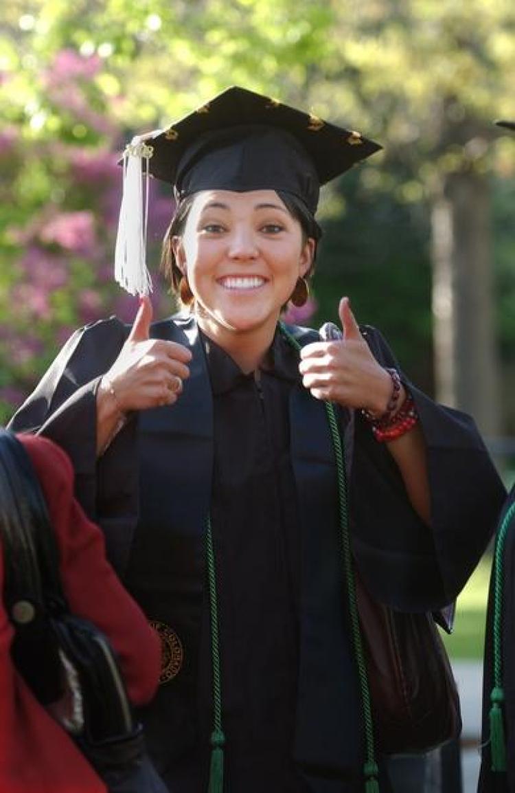 A CU student giving a thumbs up sign at graduation