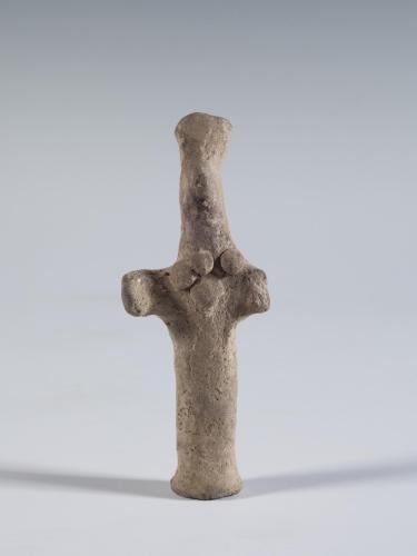 Photograph of terracotta female figurine, frontal, against a neutral gray background.