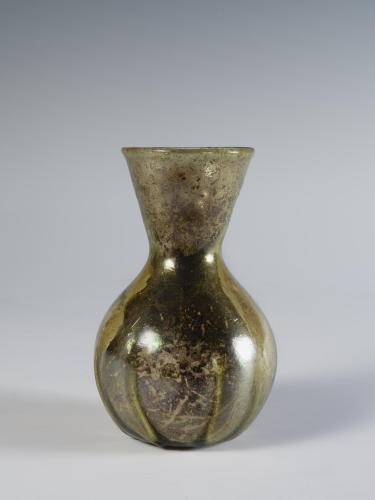 Photograph of glass vase, with flat bottom, rounded body, and neck with straight sides that flare outward to mouth, from the side against a neutral gray background.