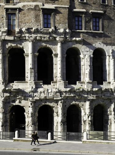 Student walking past the ancient wall and arches of Marcellus