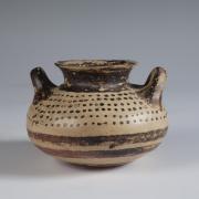 Photograph of squat jar, tan with brown slip decoration, from the side against a neutral gray background.