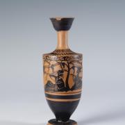 Photograph of a lekythos, focused on main decorative panel on body, from the side against a neutral gray background.