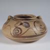 Photograph of squat jar, tan with brown slip decoration, from side against neutral gray background.