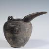 Photograph of grey-ware spouted jug, glossy black covers its entirety, from the side against neutral gray background.