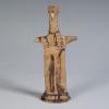 Photograph of terracotta female figurine, frontal, against neutral gray-blue background.