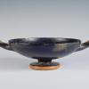 Photograph of a black-gloss kylix, from the side against a neutral gray background.