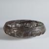 Photograph of a dark glass bowl, from a slightly raised angle against a neutral gray background.