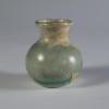 Photograph of clear glass vessel with rounded body and base and short neck that flares to a rounded mouth, from the side against a neutral gray background.