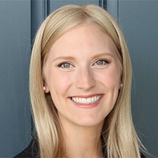 Headshot of Jordan in a dark suit against a blue backdrop.