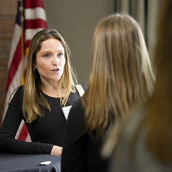 A female alumnus speaks to a student one on one during a break in the agenda.