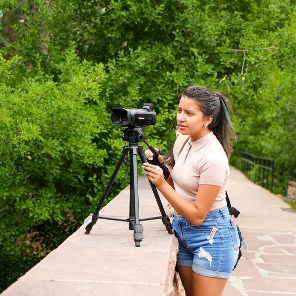 Pathways student Juanita Hurtado tests out a camera on Varsity Bridge during a journalism class.