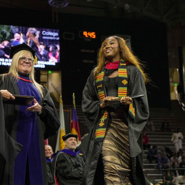 A CMCI graduate holds a diploma cover after crossing the stage.