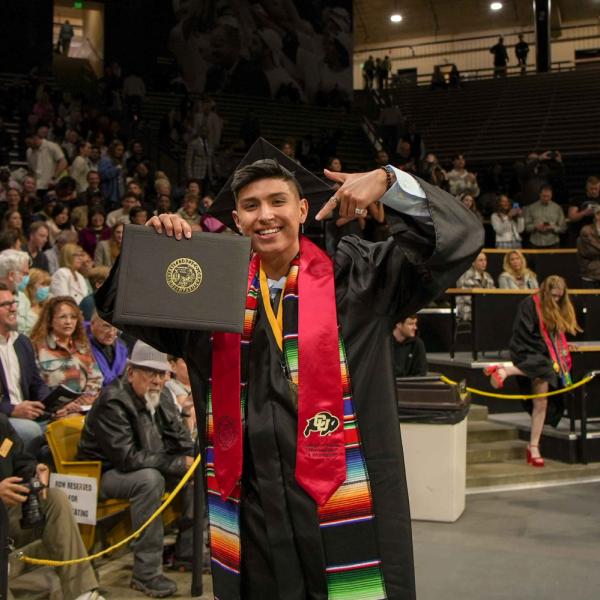 A CMCI graduate poses with a diploma cover.