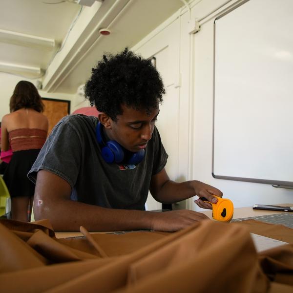 Pathways participant Samson Kidane cuts fabric while making a flag during a media studies class.