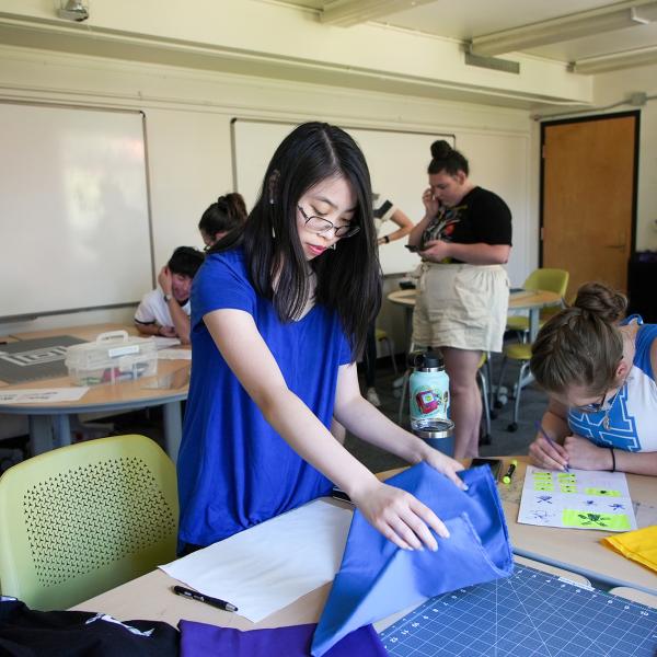 Pathways student Amy Kibort cuts her fabric while making a flag for Assistant Professor Steven Frost’s media studies class.