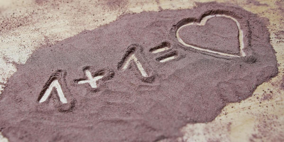 Image of the one plus one equals heart drawn in sand. Photo by Pixabay.