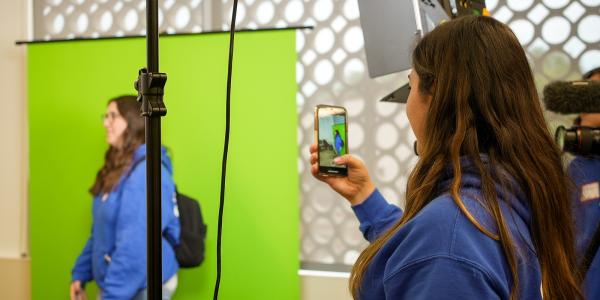 Two students test out a green screen and professional camera gear at J-Day.