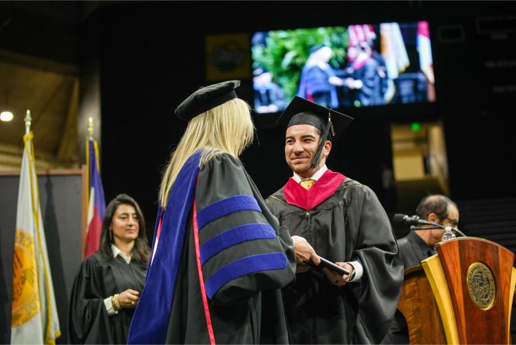 CMCI graduate student receives his diploma cover from the dean