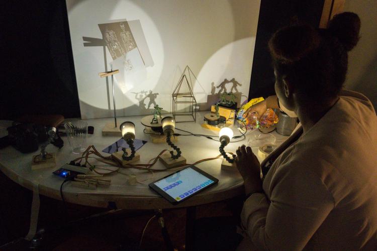 A woman arranges items on a table and uses an iPad to control lights.