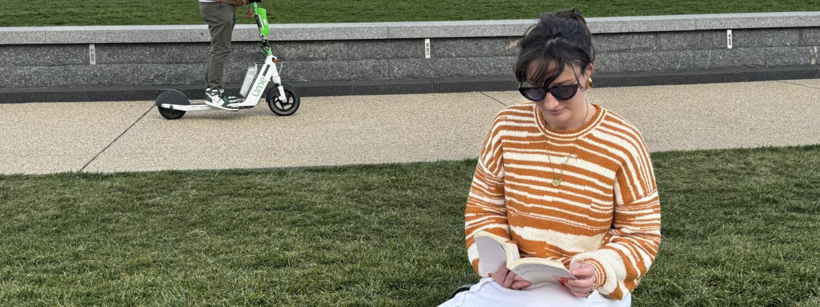 A student reads on the lawn in front of the Washington Monument