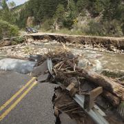 The aftermath of the Boulder floods of 2013. A damaged road is in the foreground as debris churns through the creek.