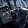 A closeup of a body camera strapped to the chest of a police officer.
