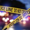 Police tape blocks off a crime scene illuminated by the blue and red lights of cruisers.