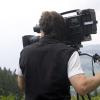 A cameraman trains his equipment on a landscape in a natural setting.