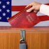 A bible being dropped into a ballot box with an American flag in the background.