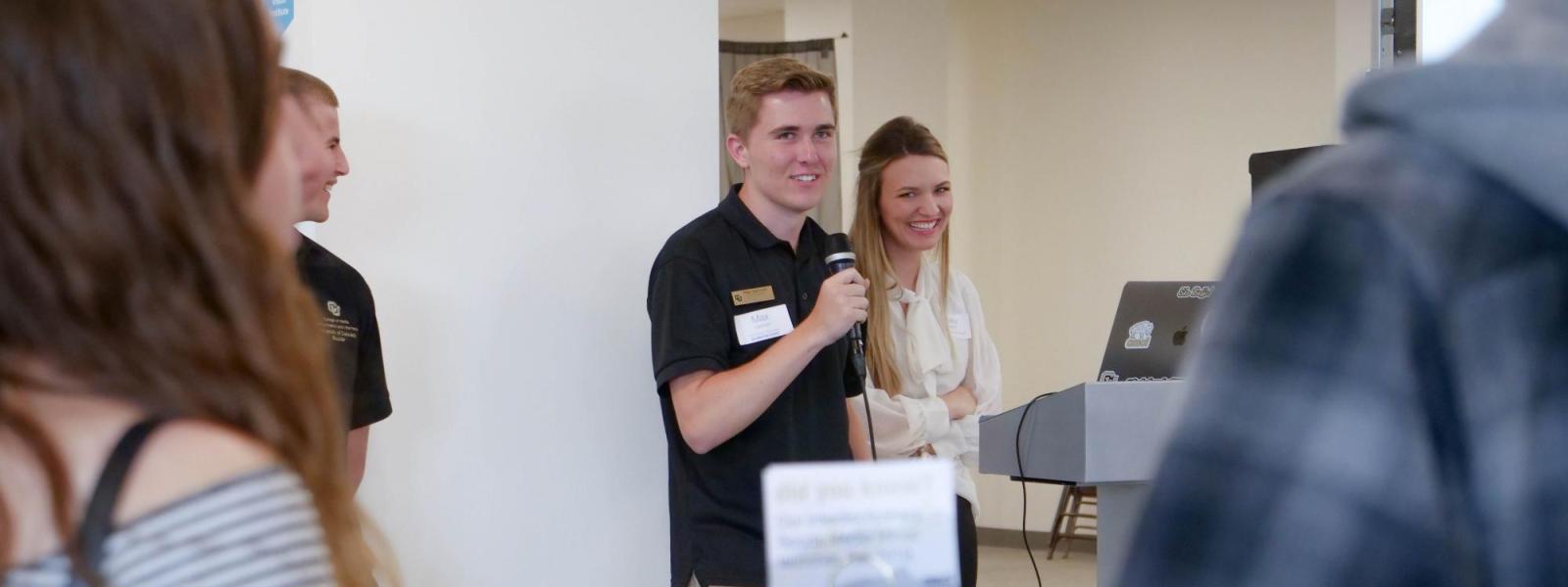 Student taking to group of people at an event. 