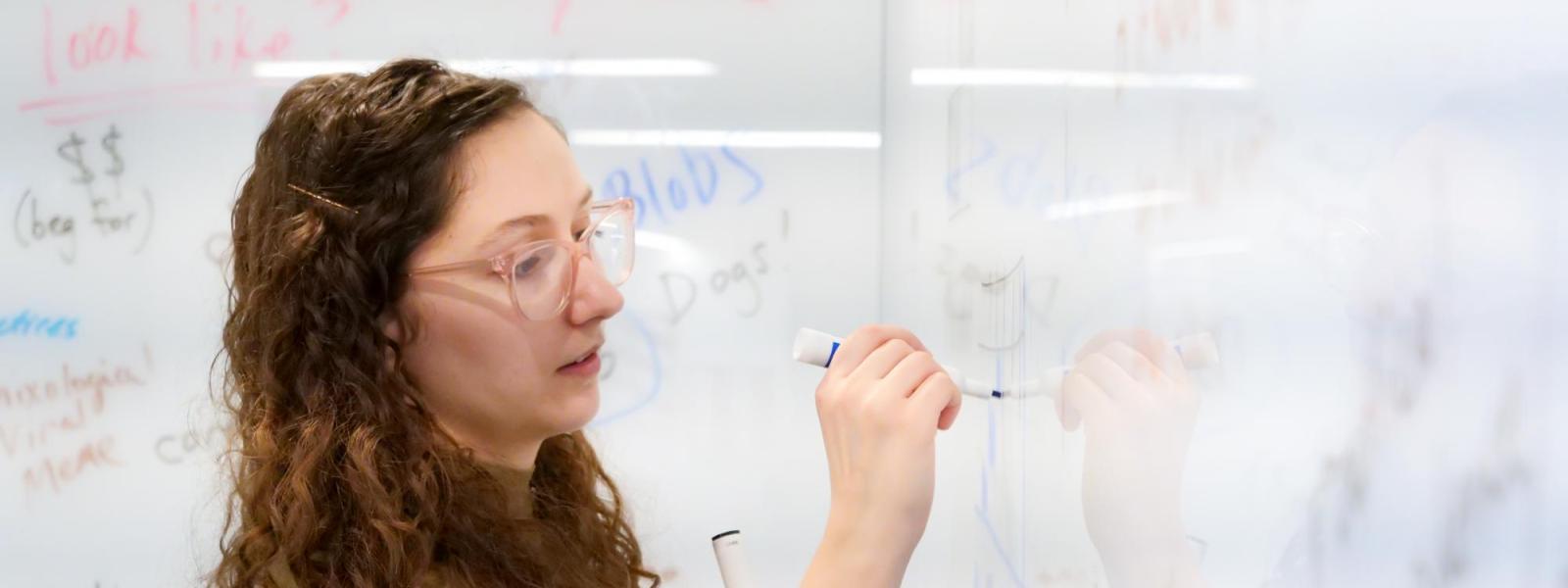 Student writing on white board during class. 