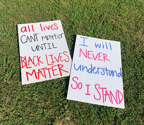 Photo with signs saying "All lives can't matter until Black lives matter" and "I will never understand so I stand"