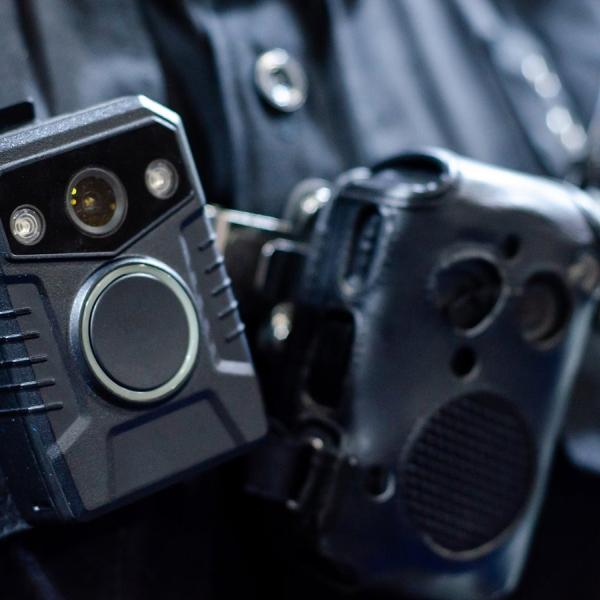 A closeup of a body camera strapped to the chest of a police officer.
