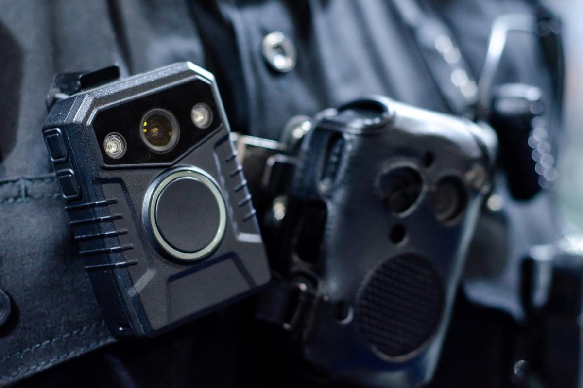A closeup of a body camera strapped to the chest of a police officer.