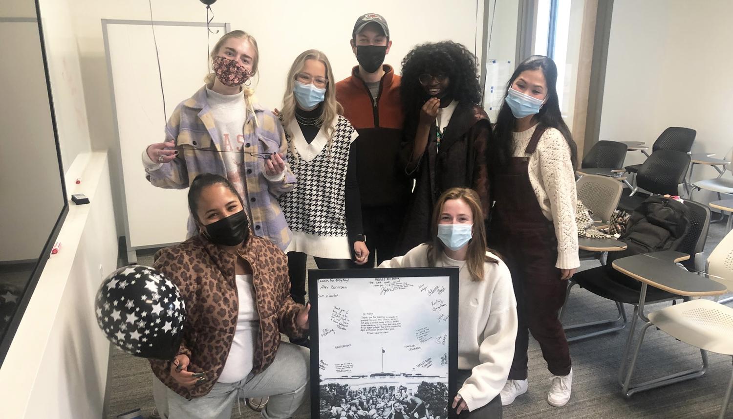 Group standing together with a signed copy of Kendrick Lamar's "To Pimp a Butterfly" album