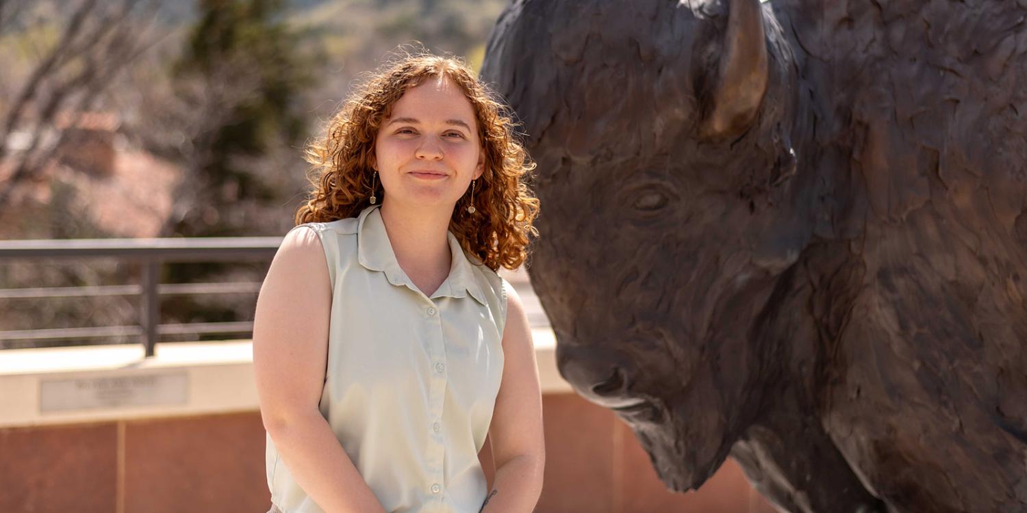 Celia poses on a rooftop next to a buffalo statue.