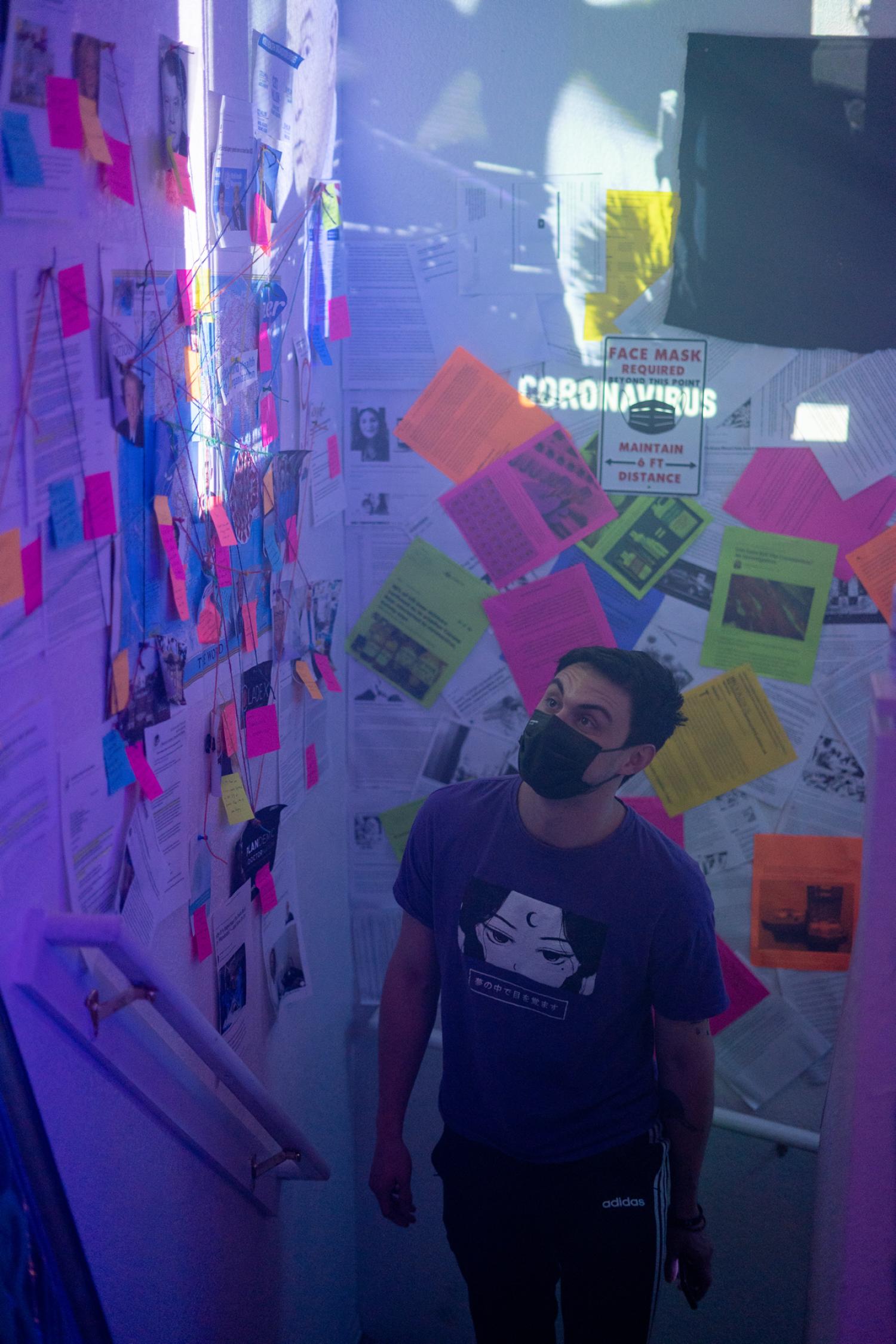 Visitors enter the ICA Loop installation via the Information Overload room, where news articles cover the walls and video clips of pandemic news coverage play on repeat. This room represents the over saturation of both accurate news and misinformation.