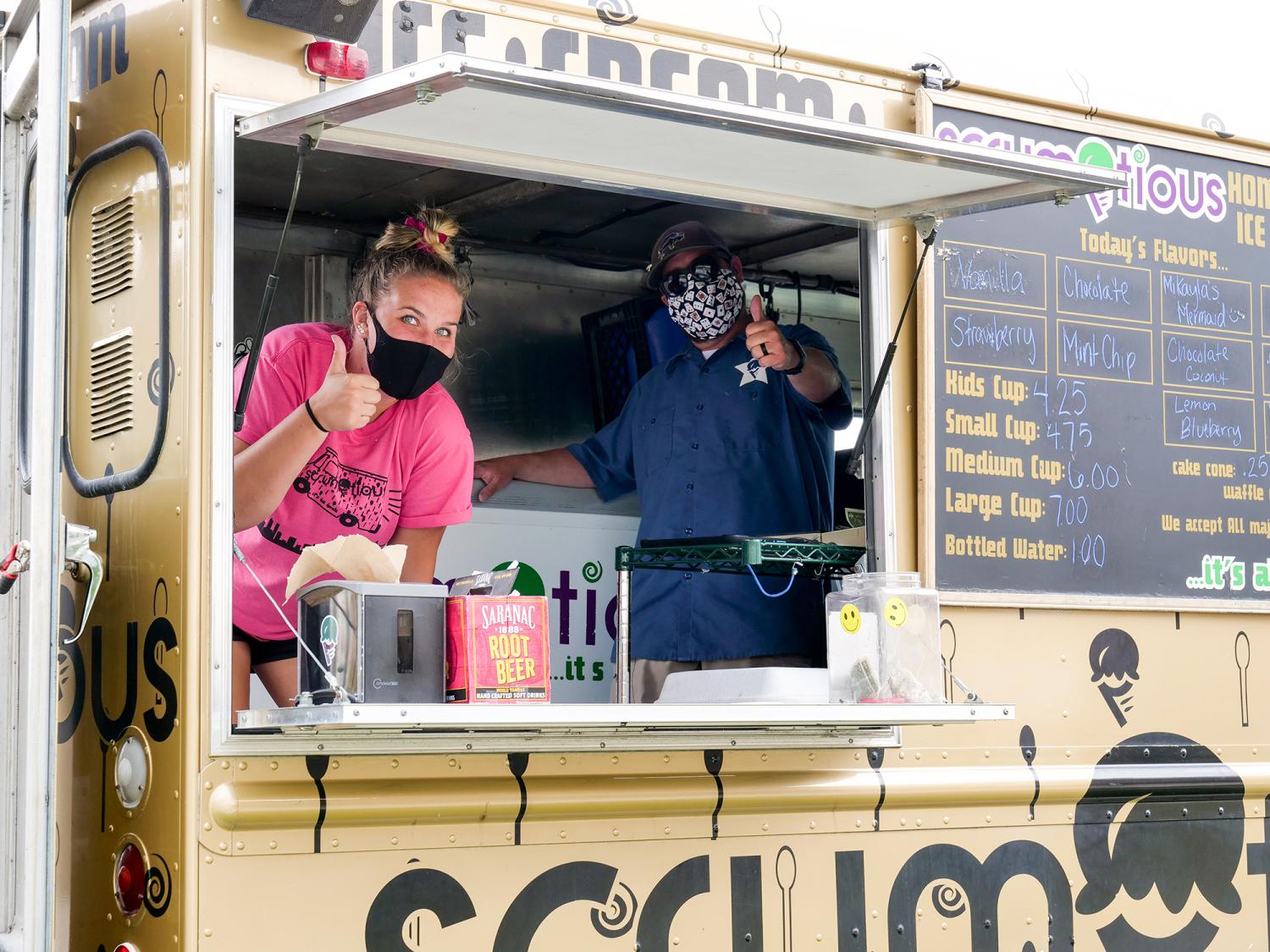 Scrumptious employees giving thumbs up inside the ice cream truck.