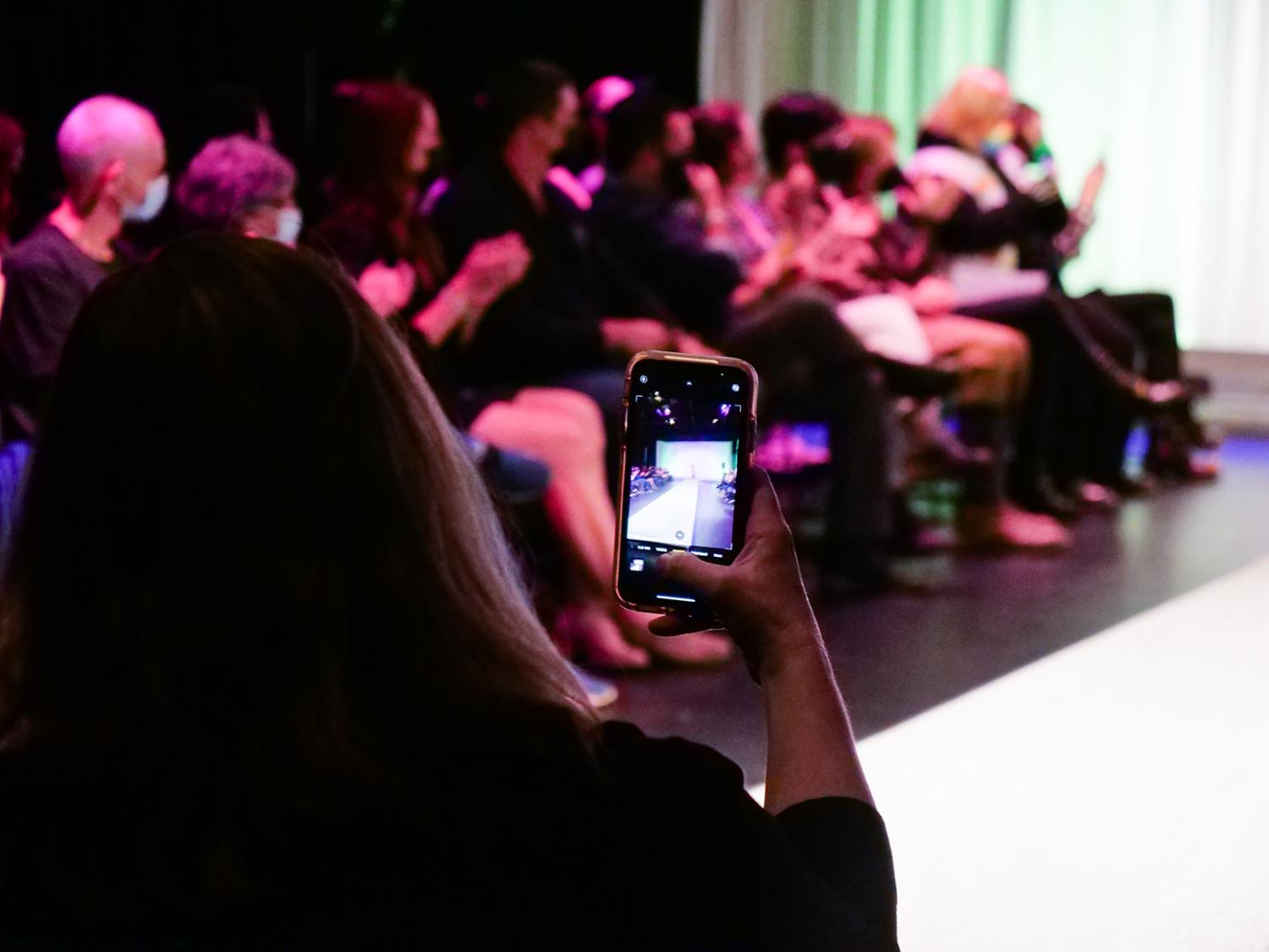 Person in the audience taking a photo with their phone