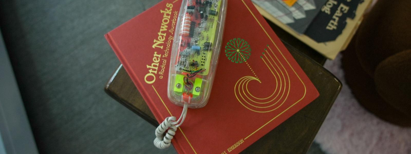 A classic clear phone handset sits on top of a book