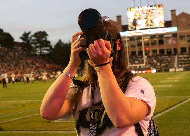 A student photographer at a CU football game. Photo by Kimberly Coffin.