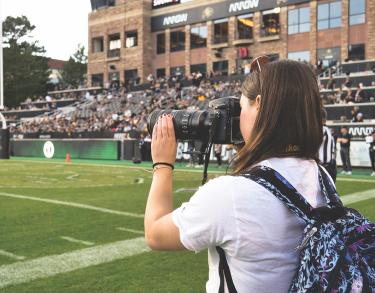 Journalism student photographs the Homecoming game in 2021. Photo by Kimberly Coffin, CMCI