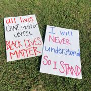 Photo with signs saying "All lives can't matter until Black lives matter" and "I will never understand so I stand"