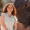 Celia poses on a rooftop next to a buffalo statue.